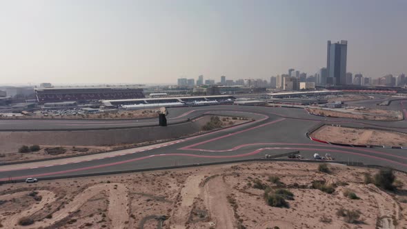 Aerial reveal of empty Dubai Autodrome race track, grand stand and Dubai skyline