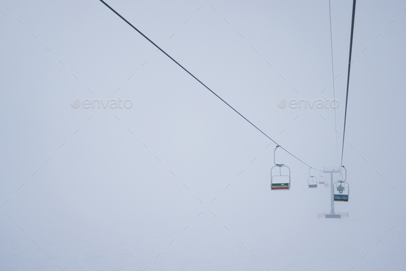 Cable cars hang on cables in a silent fog