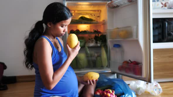 A Young Pregnant Woman Organizing Fruits and Vegetables in the Refrigerator alt