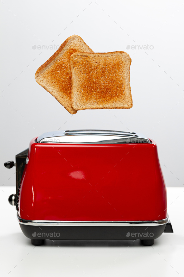 Two toasts jumping out of red toaster against white background Stock
