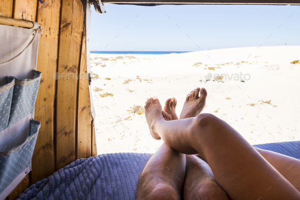 Legs point of view of romantic couple inside old van enjoying the beach and ocean parking