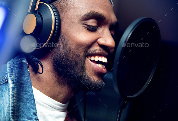 ABearded afro american man singing to microphone recording song in music studio production
