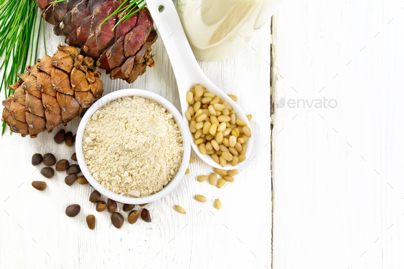 Flour cedar in bowl and nuts in spoon on light board top - Stock Photo - Images