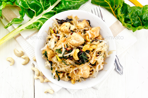 Funchoza with chard and meat in bowl on light board top - Stock Photo - Images