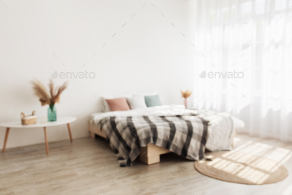 Cozy home interior and minimalist style. Double bed with pillows and blanket, tables with dry plants