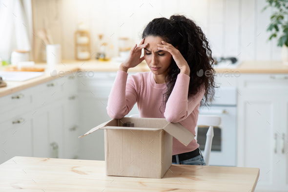 Wrong Item. Frustrated Young Woman Looking At Open Parcel With Despair