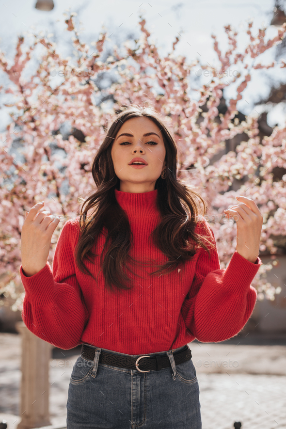 menu Doven noget Woman in great mood poses near cherry blossoms. Curly lady in jeans and red  sweater looking into ca Stock Photo by look_studio