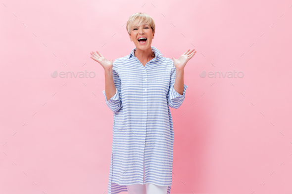 Short haired lady in plaid shirt happily posing on pink background