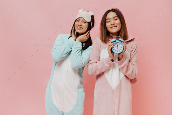 Pretty brunette Asian girls in sleep wears smile sincerely. Young women in white pajamas pose on pi