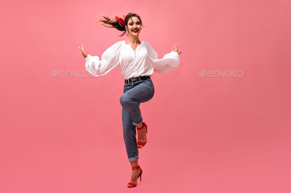 Wonderful woman in good mood dancing on pink background. Smiling lady in wide-sleeved blouse and re