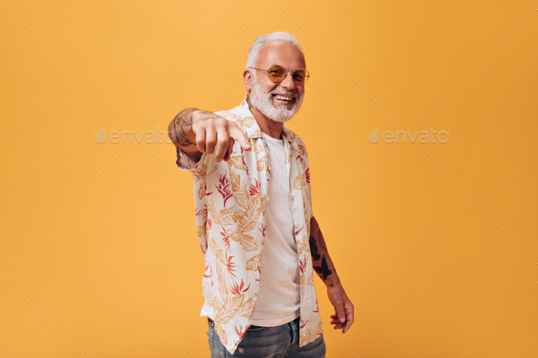 Portrait of positive man in plant print shirt pointing to camera. Photo of handsome guy in bright s