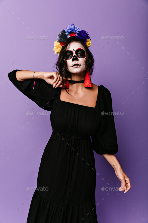Pathetic Mexican woman in black dress with crown of flowers looking at camera. Full-length portrait