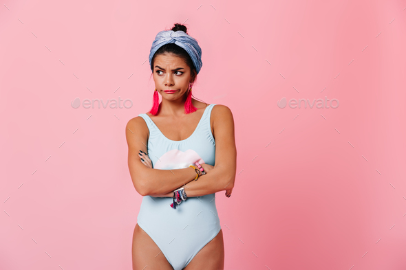 Upset lady in swimsuit standing with crossed arms.