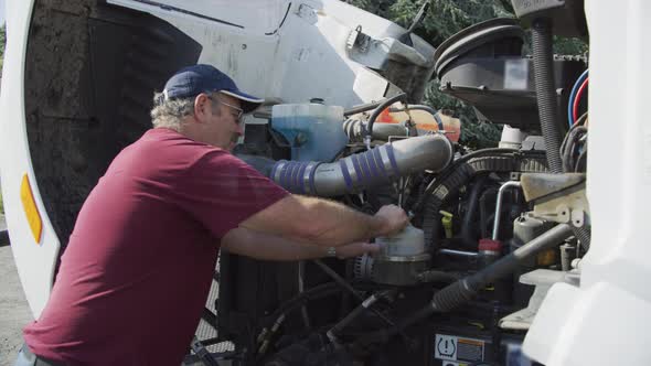 Truck driver with hood of semi truck open inspecting engine.  Fully released for commercial use.