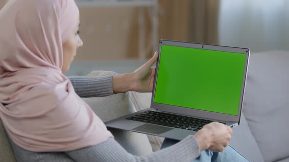 Serious Muslim Girl in Hijab Woman Freelancer Developer Sitting on Couch Home Office Using Laptop alt