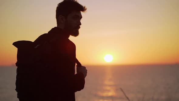 Attractive Man Standing Against the Raising Sun Smiling Looking to the Side Backlighting Slow Motion alt