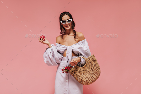 Trendy woman in white sunglasses, modern blouse, long striped skirt posing with cute smile and hold