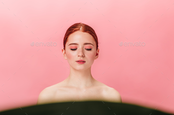 Front view of naked ginger woman looking down. Studio shot of relaxed