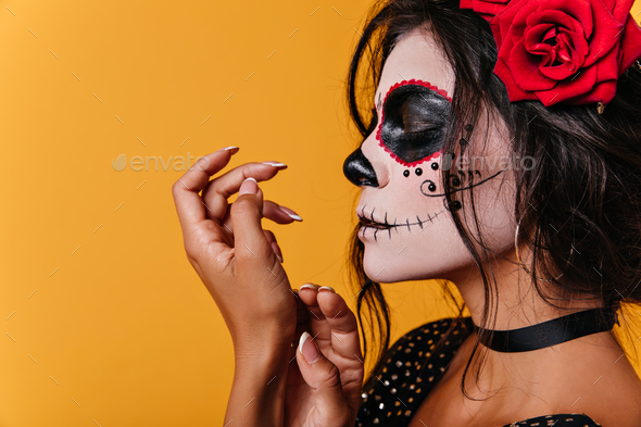 Tanned Mexican woman with traditional skull on her face poses in ...