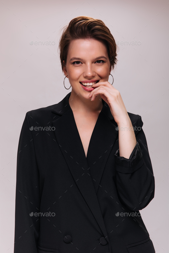 Charming woman looks into camera and smiles. Caucasian short-haired lady in black jacket laughing a
