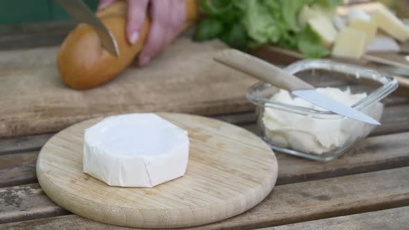 Stylish woman make a snack with bread and cheese on a table in outdoor alt