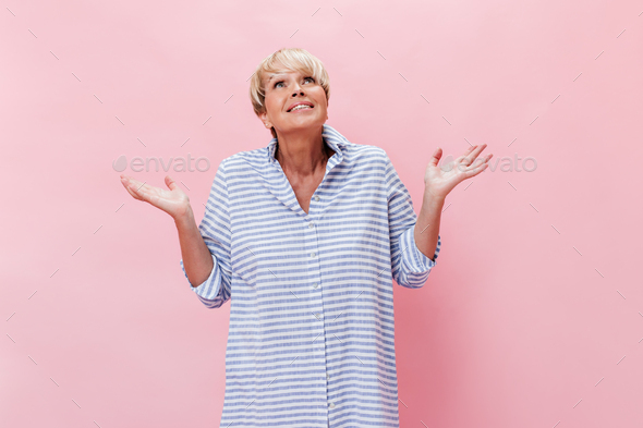 Lady in plaid shirt poses with misunderstanding on pink background