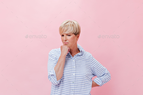 Thoughtful Lady in plaid shirt poses on pink background