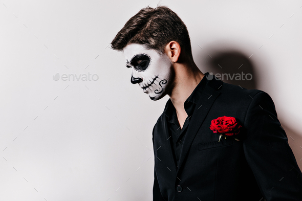 Short-haired man with muerte makeup posing with sad face expression. European guy celebrating hallo