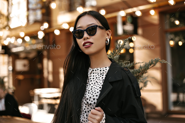 Cute Tanned Asian Woman In Black Trench Coat And White Dress Poses Outside Portrait Of Brunette La Stock Photo By Look Studio Cute Tanned Asian Woman In Black Trench, Black Trench Coat White Dress