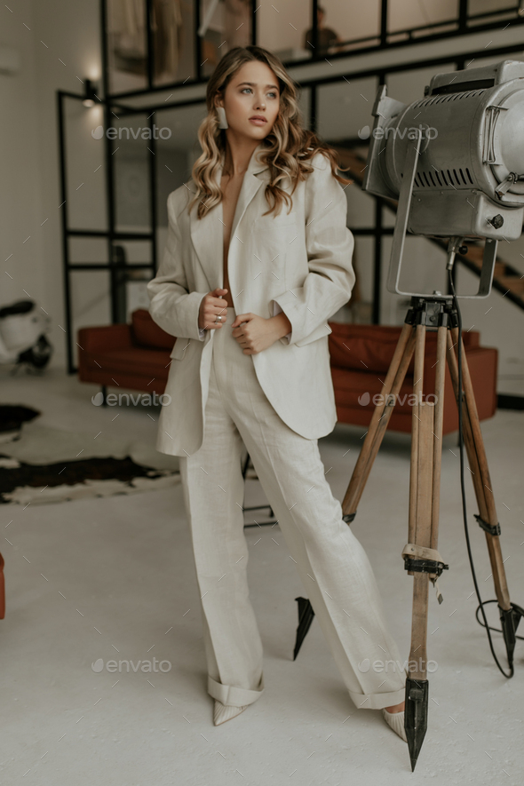Attractive woman in stylish loose beige pants and oversized linen jacket looks away and stands in m
