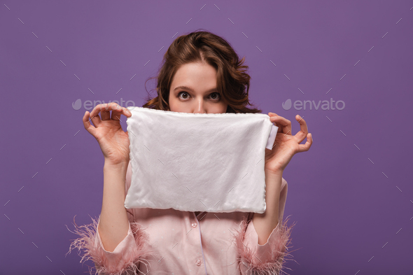 Girl making procedures isolated over violet background. Dark-haired lady with pink shirt holding wh