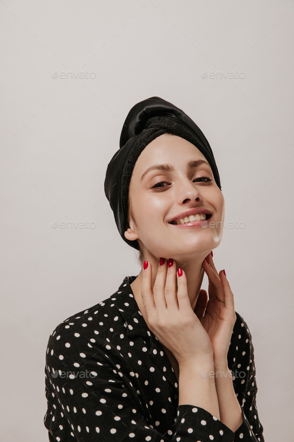 Pretty young girl with black silk towel, polka dot shirt, red manicure and clean face looking strai