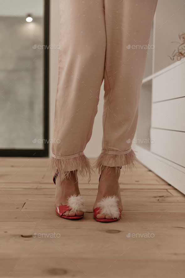 Photo of female thin legs in stylish loose pink polka dot pajama pants and red trendy home high hee