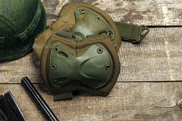 Military knee pads on wooden surface close up