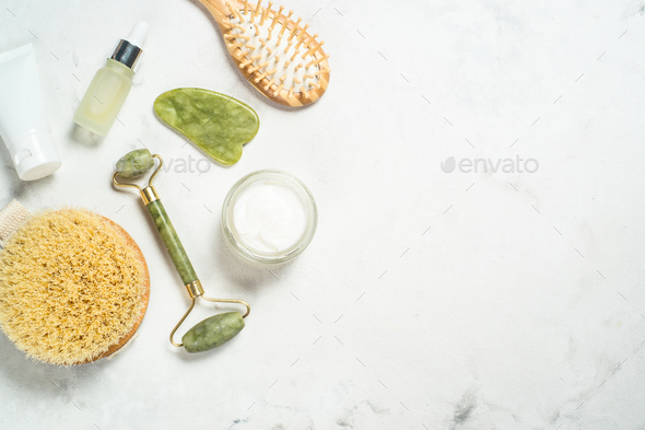 Jade roller and gua sha stone massager with face cream and serum bottle - Stock Photo - Images