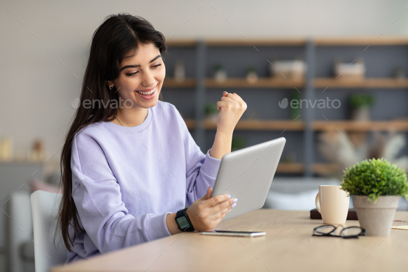 Woman using tablet celebrating success shaking fists