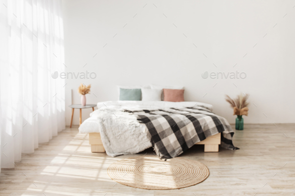 Contemporary boho design in minimalist. Bed with pillows and blanket, table with dry plants in vases