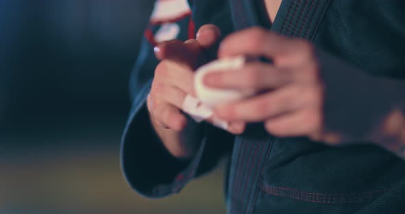 Male Athlete Wraps an Elastic Bandage on His Fingers Protection Before the Fight alt
