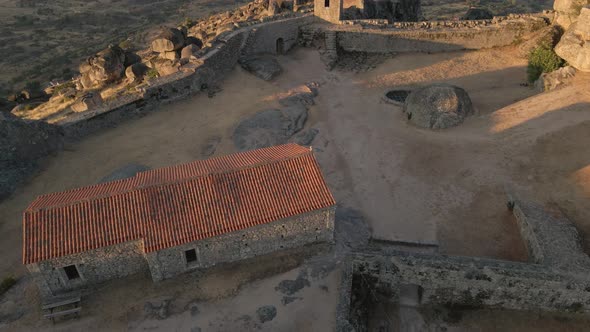 Aerial orbit around old building at Monsanto ruins during sunrise, Portugal alt