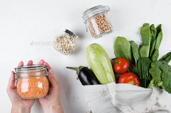 Woman holding jar with lentils. Vegetables in bio eco cotton reusable bag. Glass jar of chickpeas