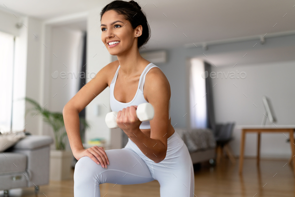 Sporty beautiful woman exercising at home to stay fit Stock Photo by nd3000