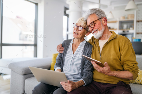 Senior couple websurfing on internet with laptop at home - Stock Photo - Images