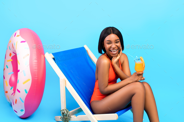 Attractive, young woman in bikini sits by the poolside on a lounge