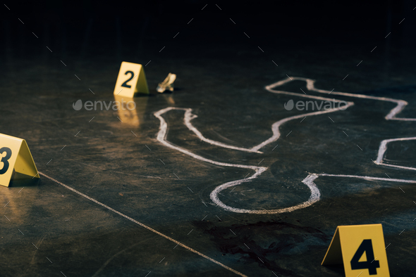 selective focus of chalk outline and evidence markers at crime scene
