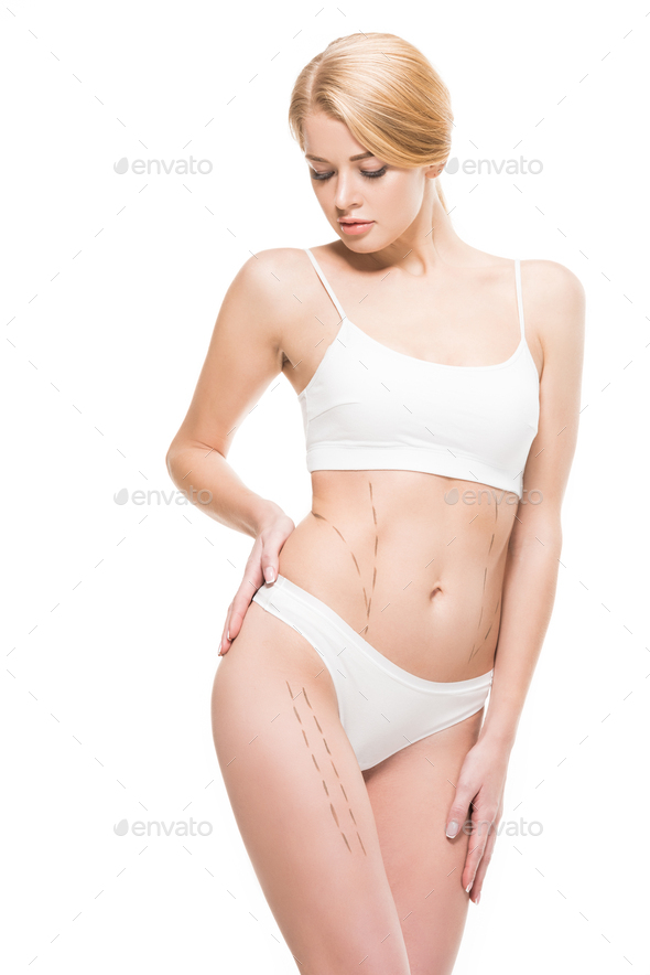 young woman in white underwear looking at correcting marks on body isolated  on white Stock Photo by LightFieldStudios