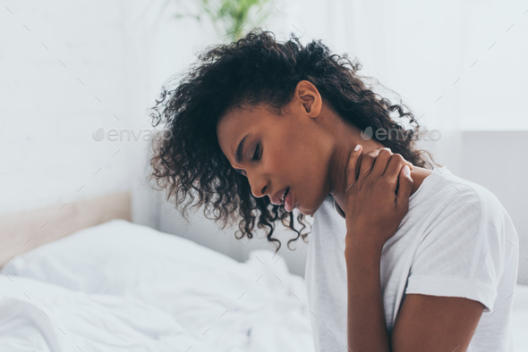 Unhappy African American Woman Suffering From Neck Pain In Bedroom ...