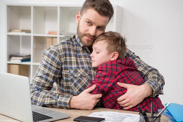 Father businessman hugs his son at home office