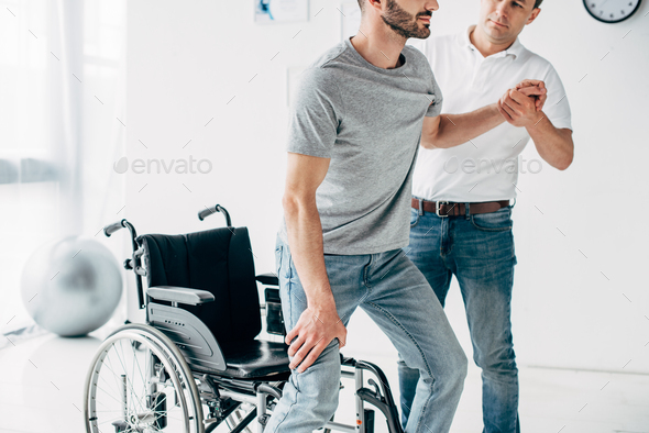 cropped view of Physiotherapist helping handicapped man during recovery