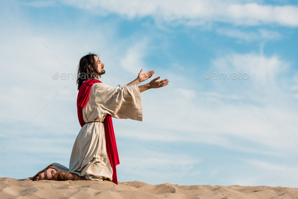 jesus praying on knees on sand in desert against sky