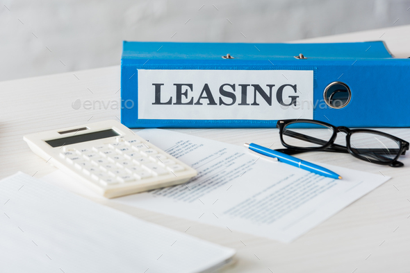 selective focus of folder with leasing lettering near calculator, pen and glasses on desk - Stock Photo - Images